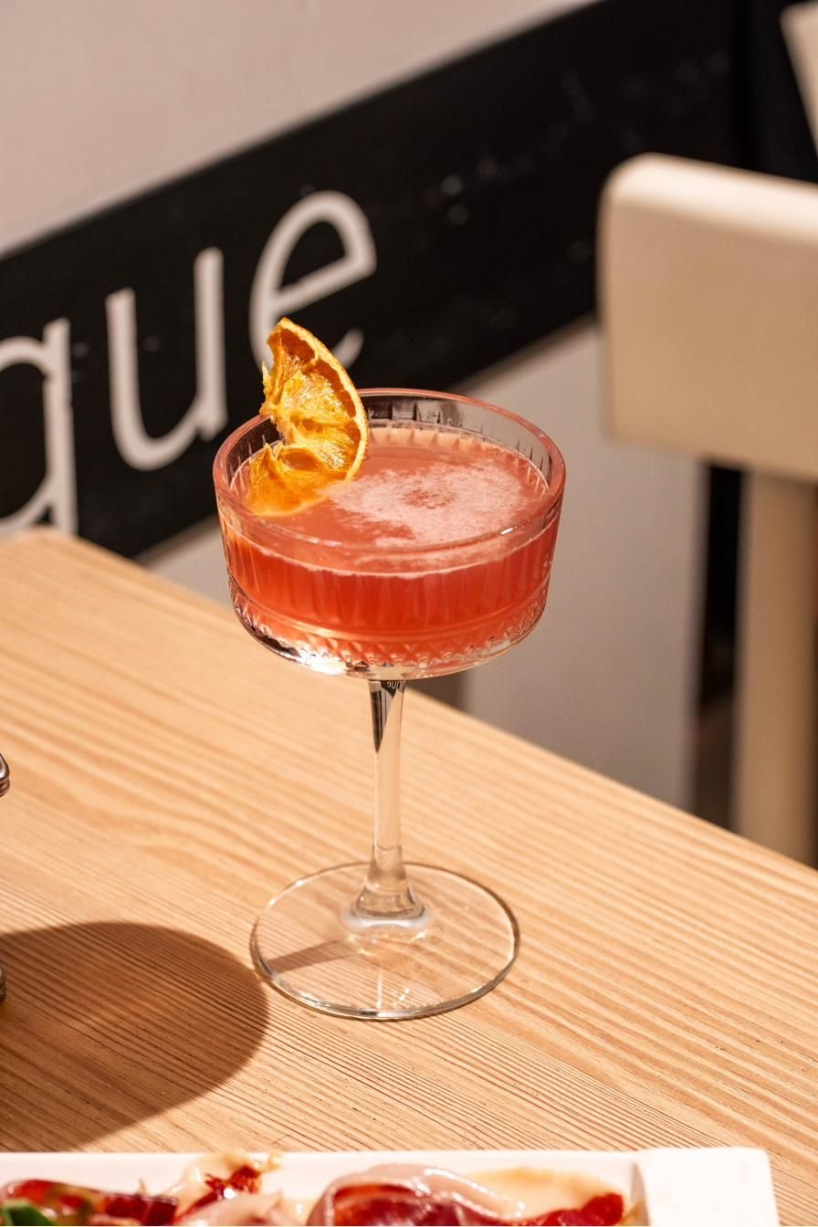 Cocktail rosa con scorza d&rsquo;arancia su un tavolo di legno