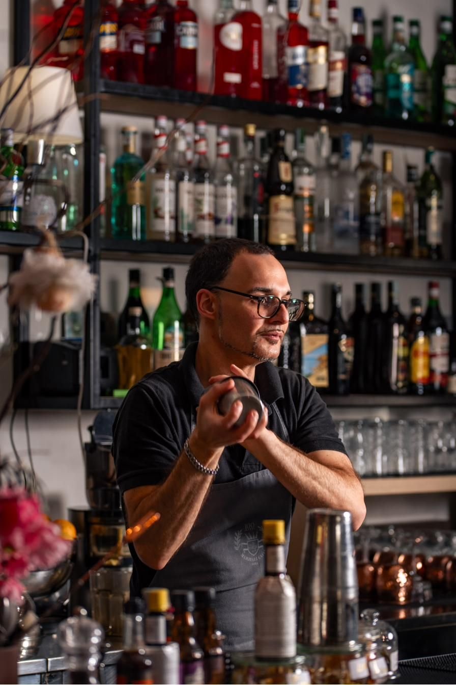 Il barman mescola un cocktail rosso in un mixing glass