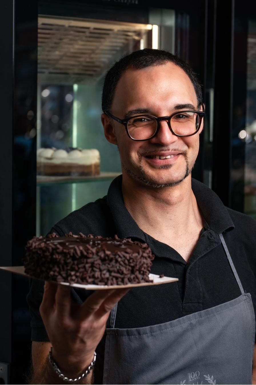 Il pasticcere mostra una torta al cioccolato